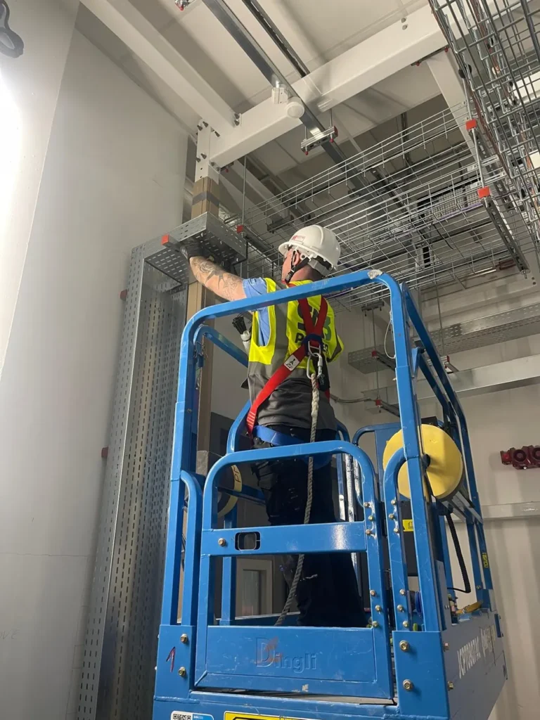 SA3 Power engineer installing cable tray from a scissor lift