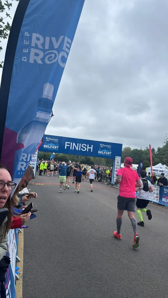 Runner crossing the finish line at the Belfast City Marathon Relay for Charis Cancer Care