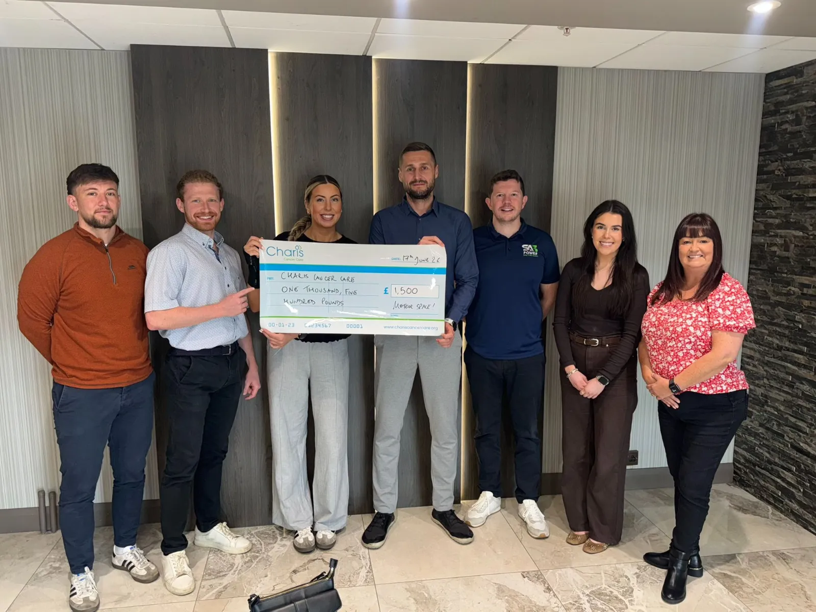 Claire from Charis Cancer Care receiving a £1,500 cheque from the SA3 POWER, Meteor Space and Canary7 Belfast Marathon relay teams