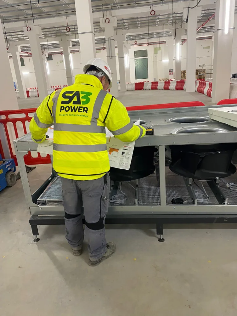 SA3 Power engineer reviewing drawings beside plant equipment on a data centre site